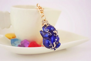 Detailed view of blue enamel pig keychain with white crystals and gold alloy clasp