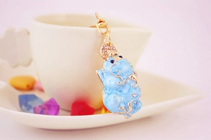 Detailed view of light blue enamel pig keychain with crystal accents and gold finish