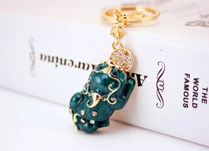 Close-up of emerald green Pi Xiu keychain with gold plating and sparkling rhinestones