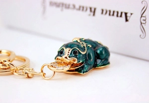 Macro view of emerald green enamel Pixiu keychain with gold plating and rhinestones