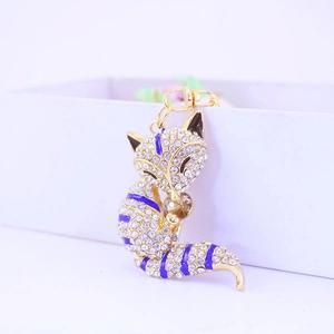 Cute golden fox keychain with white crystals and blue enamel stripes on white background
