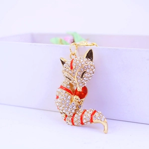 Sparkling fox keychain with gold alloy, white crystals and red enamel accents on a gift box