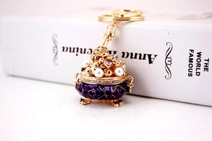 Detail shot of a purple enamel jar keychain with white pearls and lavender crystals