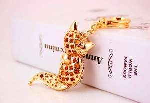 Detail of fox-shaped golden keychain with hollow clover pattern and sparkling crystals