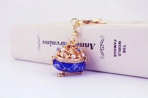 Detail of blue enamel keychain with gold vintage patterns, pearls, and rhinestones