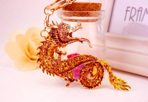 Detailaufnahme des goldenen Drachen-Schlüsselanhängers mit gelben Strasssteinen und blauen Augen