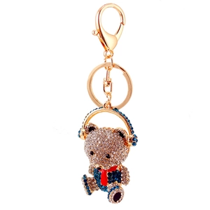 Golden bear keychain with sparkling crystals, blue headphones, and a red scarf accessory