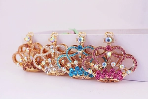 Dettaglio di quattro portachiavi a corona con strass colorati e base in metallo dorato