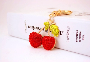Macro shot of red crystal cherry keychain with gold hardware on a book edge