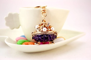 Detailed view of purple enamel incense burner keychain with pearls on a coffee cup