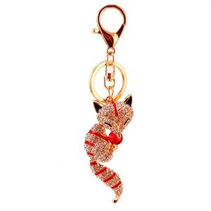 Sparkling crystal fox keychain with gold metal base and red enamel details on white background