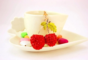 Detail view of sparkling red rhinestone cherry keychain with golden leaf and lobster clasp