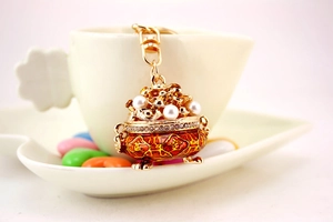 Detailed macro view of an enamel incense burner keychain with white pearls and rhinestones
