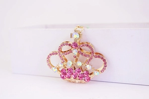 Dettaglio del portachiavi corona dorata con strass rosa e design in metallo traforato