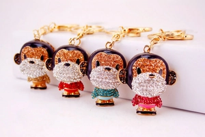 Detail view of four crystal monkey keychains in gold, red, blue and pink finishes