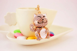 Detailed close-up of golden Maneki Neko keychain with rhinestones and white enamel