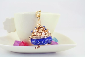 Close-up of blue enamel treasure basin keychain with pearls hanging on a coffee cup