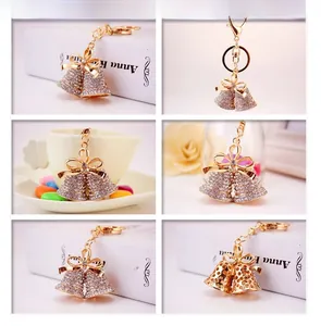 Macro detail of gold-plated bell keychains with sparkling crystal bow ties on a table