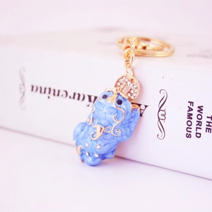 Blue Pi Xiu keychain with gold metal lines and sparkling rhinestones on white books