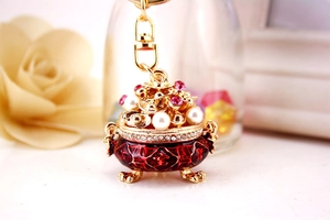 Detail view of golden treasure basin keychain with red enamel and pearl accents
