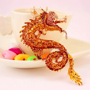 Goldener Drachen-Schlüsselanhänger mit orangefarbenen Kristallen am Tassenrand