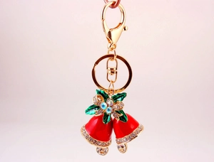 Detail of red enamel Christmas bell keychain with green leaves and sparkling rhinestones