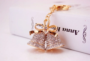 Close-up of golden double bell keychain with sparkling rhinestones and a ribbon bow