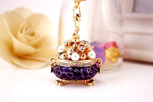 Macro shot of gold-plated incense burner keychain with purple enamel and pearls