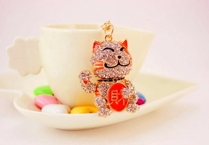 Close-up of golden Maneki Neko keychain with rhinestones and wealth symbol detail