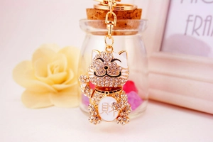 Detailed close-up of golden lucky cat keychain with sparkling crystals and fortune symbol