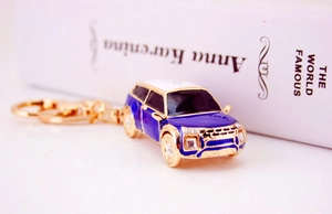Dettaglio ravvicinato del portachiavi auto blu con strass e anello dorato su sfondo bianco