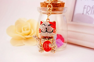 Close-up of golden lucky cat keychain with sparkling crystals and red enamel detail