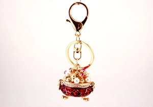 Macro detail of golden incense burner keychain with red enamel and pearl inlay