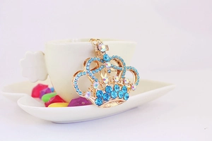 Dettaglio di un portachiavi a corona dorata scintillante con strass blu chiaro e cangianti