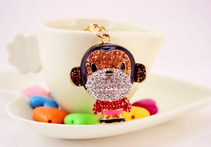 Macro shot of sparkling monkey keychain with crystals hanging on a white ceramic mug
