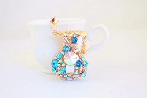 Detailed close-up of a golden money bag keychain with colorful crystals and a dollar charm