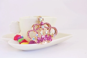 Dettaglio di un portachiavi a corona con strass rosa e cristalli iridescenti su oro