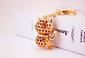 Detail of golden hollow fortune cat keychain with clover pattern and spring clasp