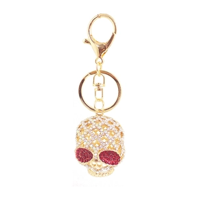Détail d'un porte-clés tête de mort doré orné de strass et d'yeux rouges brillants