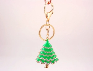 Close-up of golden Christmas tree keychain with green enamel and sparkling rhinestones