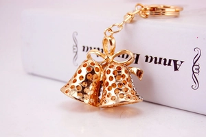 Detail view of golden hollow Christmas bells keychain with ribbon bow and rhinestones