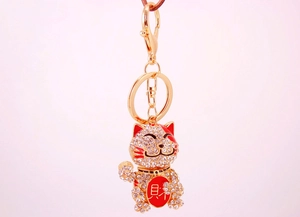 Close-up of golden lucky cat keychain with crystal rhinestones and red enamel detail