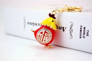 Dettaglio del portachiavi a forma di pollo in smalto rosso con carattere Fu e cristalli