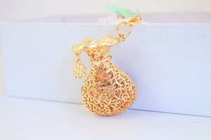 Macro shot of gold hollow money bag pendant with dollar sign charm and intricate filigree
