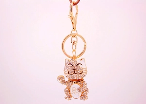 Detailed view of lucky cat keychain with sparkling crystals and golden metal finish