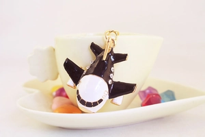 Detailed close-up of a black and white enamel airplane pendant with mini rhinestones