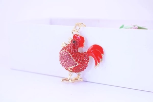 Close-up of rooster keychain with red rhinestones and gold-plated enamel details