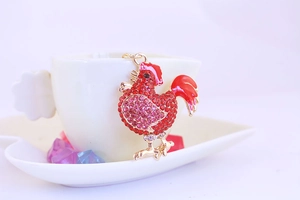 Macro shot of sparkling crystal-studded rooster keychain with red enamel details