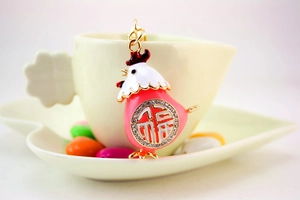 Dettaglio ciondolo pulcino smaltato con carattere Fu e strass su una tazza bianca