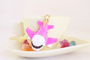Detail of pink and white enamel airplane pendant with rhinestones on a ceramic cup